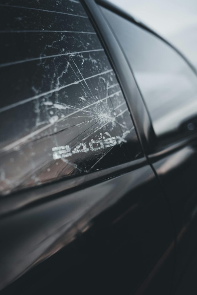 Close-up shot of a damaged Nissan 240SX window with shattered glass, emphasizing the texture and automotive details.